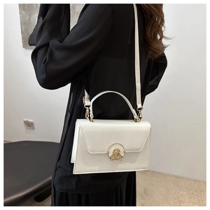 Stylishly boxy white leather handbag with golden buckle worn on shoulder by model