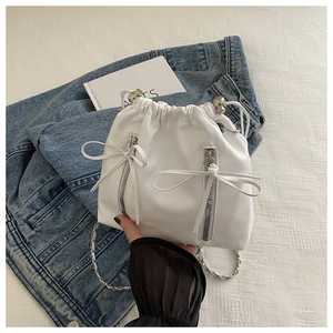 Detailed shot of white bucket backpack with decorative zippers and soft ribbon bows