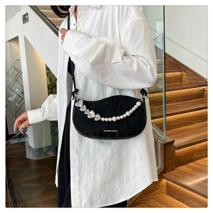 Detail of black half-moon shoulder bag with pearl heart chain and minimalist logo