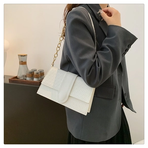 Detail of white rectangular shoulder bag with woven texture and gold chain strap