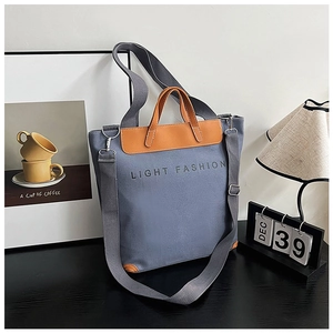 Detail of canvas tote bag showing zipper closure with premium leather stitching and handle