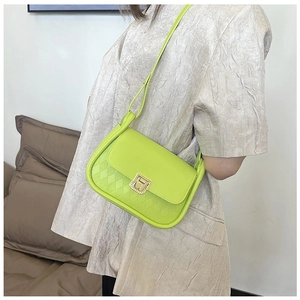 Detail view of neon green crossbody bag with quilted texture and gold clasp on a model