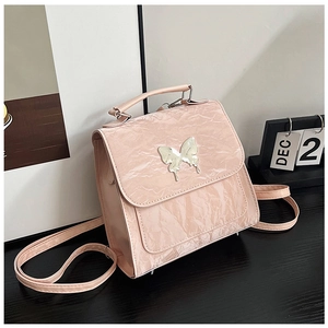 Detail of pink crinkled leather bag featuring a silver butterfly buckle and top handle