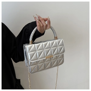 Detail of silver quilted crossbody bag with golden hardware and woven handle