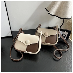 Detail view of contrast saddle crossbody bags in beige and coffee faux leather