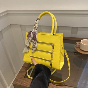 Detail of yellow crossbody bag with triple gold zippers and silk scarf handle wrap