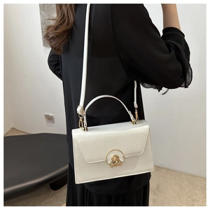 Polished white box bag with golden metal lock shown on shoulder for fashion styling