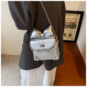 Detail of silver metallic crossbody bag with bow decoration and chunky chain strap