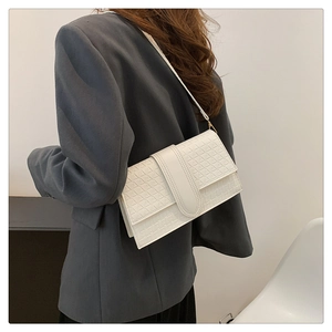 Detail shot of white woven texture shoulder bag with triangular pattern worn on model