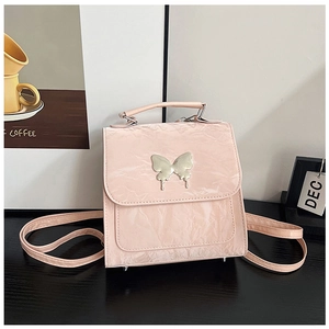 Close-up of pink pleated leather backpack with silver butterfly detail and metallic studs