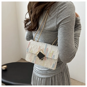 Fashionable crossbody bag featuring colorful vertical stripes and a gold chain strap