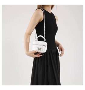 Close-up of white quilted mini vanity bag with silver butterfly clasp and chain strap