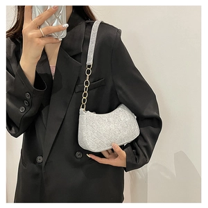 Close-up of light grey tweed half-moon bag featuring quilted patterns and gold chain strap