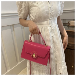 Detail of fuchsia leather handbag with gold ring lock shown with a white lace dress