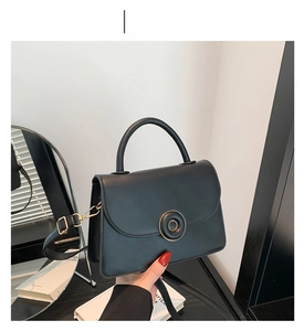 Vue détaillée du sac en cuir noir avec fermoir doré et poignée supérieure courbée