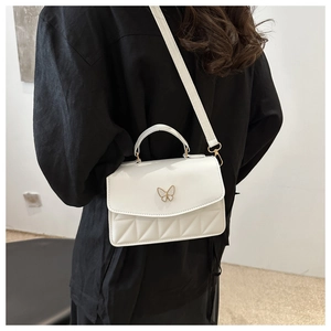 Detail of white butterfly quilted crossbody bag with golden hardware and elegant texture