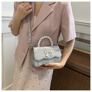 Detail of silver textured mini bag with pearl handle and metal butterfly ornament