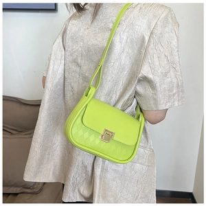 Detail of neon green crossbody bag showing quilted texture and gold metal clasp