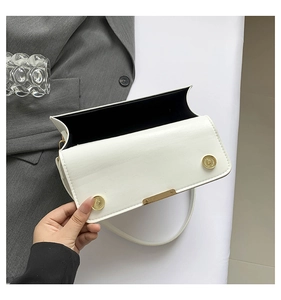 Detail of white PU leather bag showing magnetic gold buckles and black interior lining