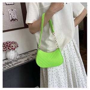 Detail of neon green chevron quilted baguette bag with adjustable strap and gold chain