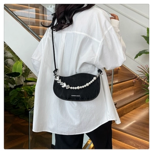 Detail of black crescent crossbody bag featuring pearl heart chain and fashion logo