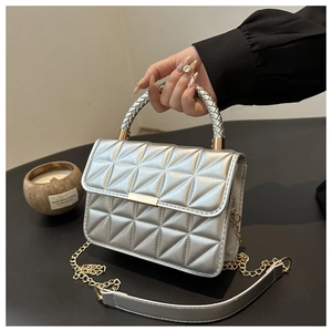 Detail of silver quilted handbag featuring metallic texture and woven handle design