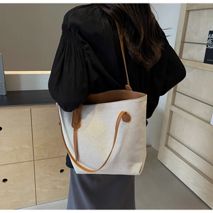Close-up of contrast canvas tote bag with brown leather handles and premium stitching
