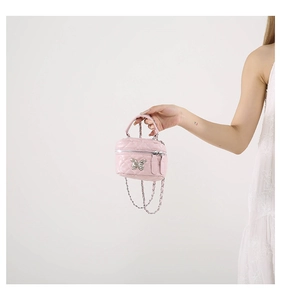 Detail of pink quilted mini bag with silver butterfly charm and chain strap