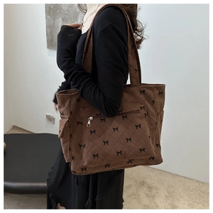 Detail of dark brown corduroy tote bag showing bow patterns and diamond quilting texture