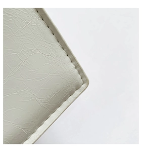 Detailed close-up of white embossed faux leather texture with fine edge stitching