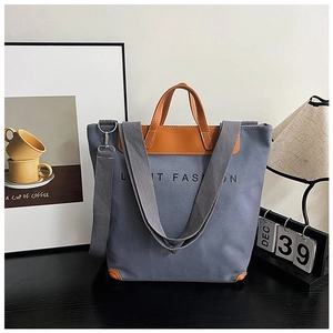 Detail of grey canvas tote bag with brown leather trim and LIMIT FASHION lettering