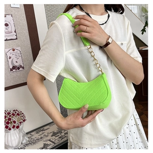 Close-up of neon green crescent shoulder bag with V-quilted faux leather and gold chain strap
