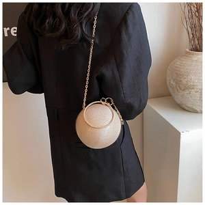 Detailed shot of champagne gold spherical evening bag with metal ring handle and chain
