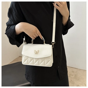 Detailed view of white quilted faux leather bag with elegant gold butterfly clasp