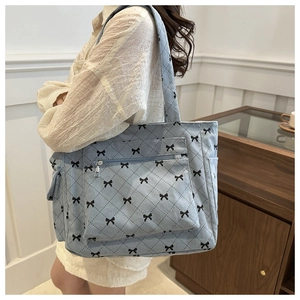 Detail of light blue corduroy tote bag with black bow print and quilted texture