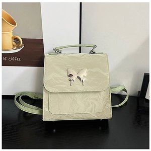 Detail of light green wrinkled leather backpack with silver metallic butterfly buckle