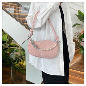 Detail view of pink pleated shoulder bag with pearl chain and heart charms on a model