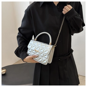 Silver quilted crossbody bag with mirror finish and gold chain strap on a model