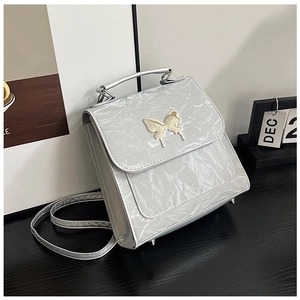 Detail of silver textured handbag featuring a cream butterfly clasp and metallic handles