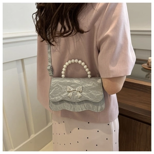 Detail of silver pleated crossbody bag with pearl handle and metal butterfly clasp