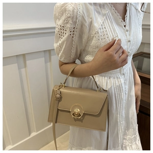 Detail view of apricot PU leather handbag featuring a gold circular metal twist lock clasp