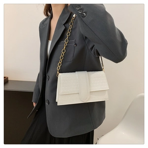 Detail of white minimalist leather bag with geometric embossing and gold chain strap