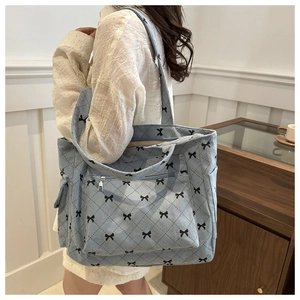 Blue corduroy tote bag detail with quilted texture and small black bow print pattern