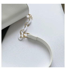 Detail of white glossy faux leather bag with acrylic and gold chain strap links