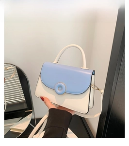 Détail du sac élégant bicolore bleu et blanc en cuir avec boucles métalliques dorées