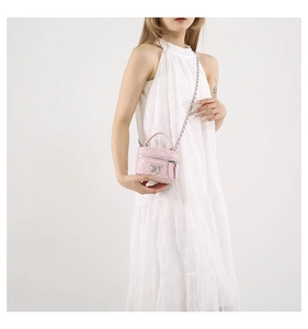 Close-up of pink quilted leather bucket bag with silver butterfly pendant and chain strap