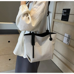 Detail of minimalist fabric tote bag with black leather straps and woven texture