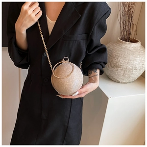 Champagne gold spherical evening clutch bag styled with a modern black suit