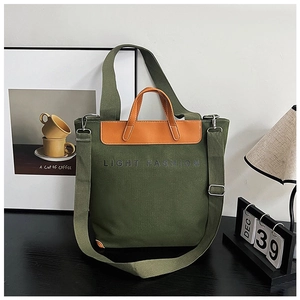 Detail of army green canvas tote bag featuring brown leather handles and adjustable strap