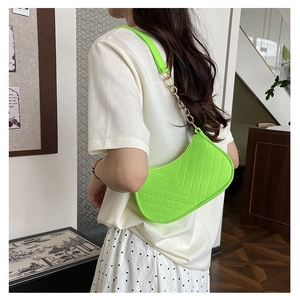 Fluorescent green quilted half-moon shoulder bag shown on model in a stylish interior
